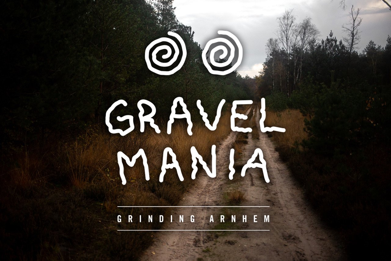 Gravel Mania poster with the 'Grinding Arnhem' logo and spiral eyes over a sandy double track through heath and pines.