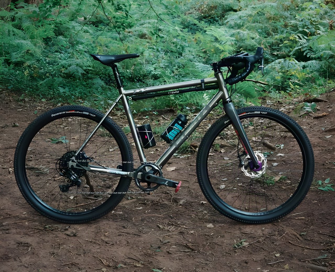 Chris Hunter's titanium Planet X Tempest gravel bike on 650b wheels, parked on a dirt track in woodland.