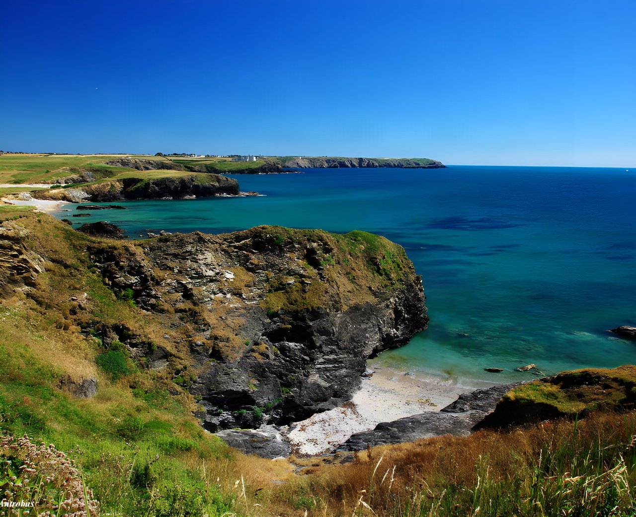 Clifftop view over a sandy cove and turquoise sea on the Cornish coast, the setting for the West Kernow Way.