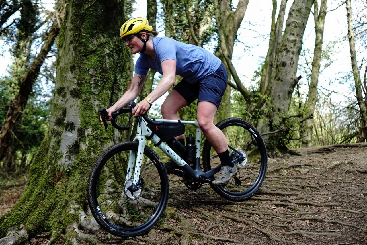 Rider in the 7mesh Elevate tee and Farside shorts descends a rooty woodland slope on a gravel bike.