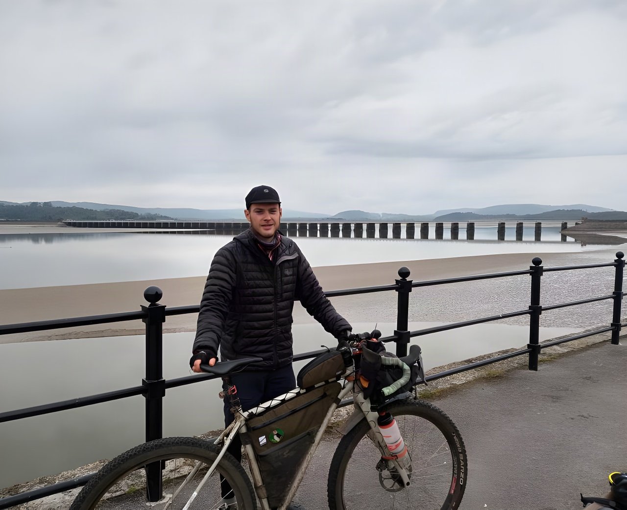 Rider with a mud-spattered bikepacking bike on the seafront at Arnside, where the Dales Divide 2021 starts.