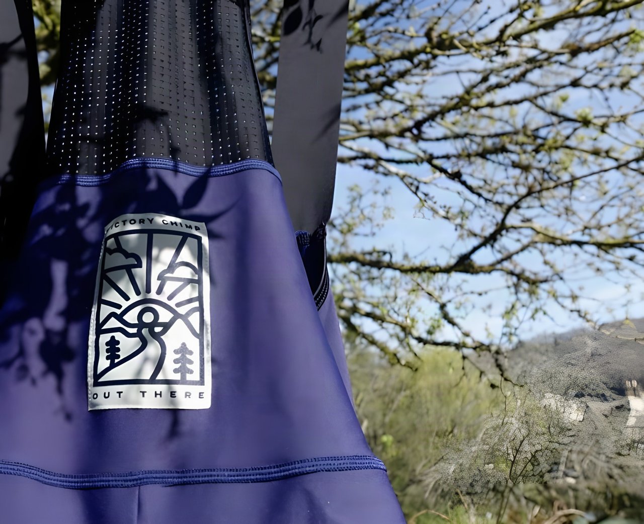 Victory Chimp Out There logo patch on the front of the navy Cargo Bib Shorts, hung outdoors under a tree.