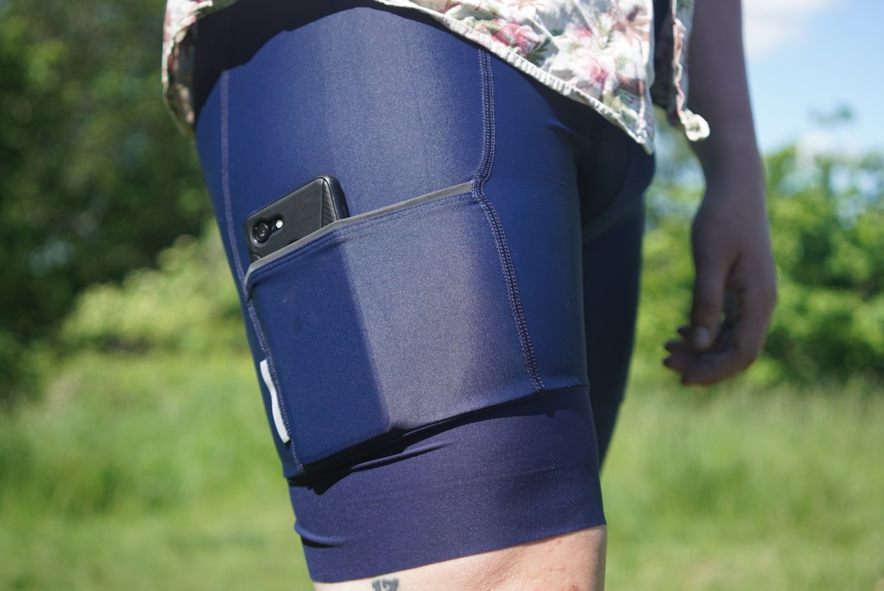 A phone tucked into the thigh cargo pocket of navy Triban RC500 bib shorts.