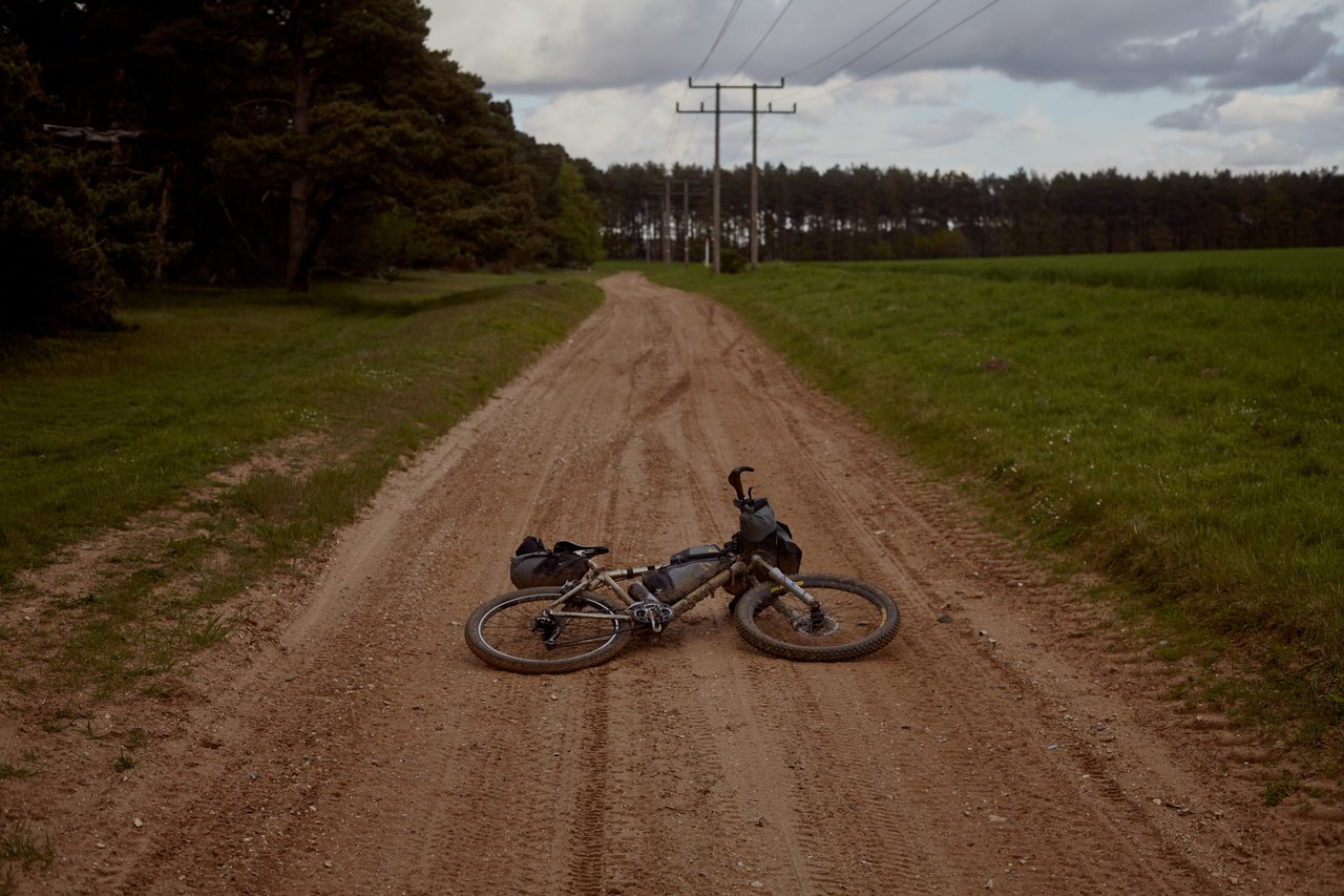 Further East endurance race: a bikepacking bike lying on a straight dirt track between flat fields, power lines above.