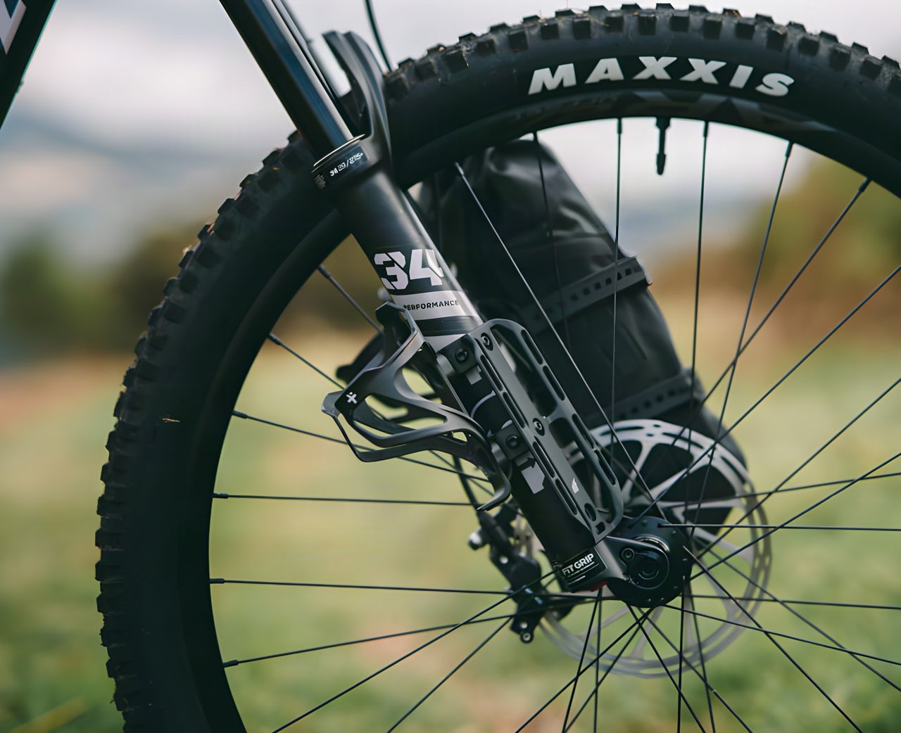 Close-up of a Tailfin Suspension Fork Mount on a suspension fork leg with a bottle cage and a drybag attached.