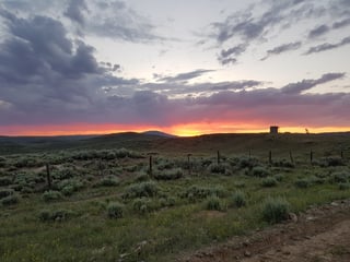Orange sunset over sagebrush hills and a dirt road on the Tour Divide route near the Wyoming/Colorado border.