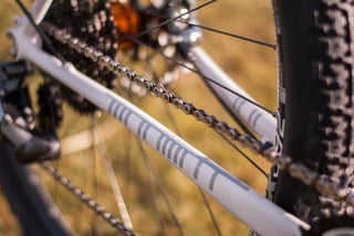 Chainstay of the Donard x Victory Chimp steel frame with grey Ogham paintwork, chain and WTB Nano tyre beyond.