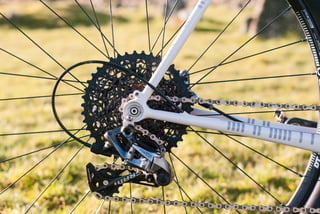 SRAM Force 1 rear mech and 10-42 cassette on the white Donard x Victory Chimp frame, seen through the wheel.