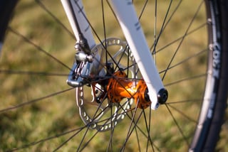 Front disc brake caliper, rotor and orange Hope hub on the white carbon fork of the Donard x Victory Chimp.
