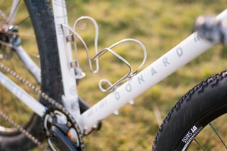 Donard lettering on the down tube above a stainless steel bottle cage, with the Hope chainring blurred behind.