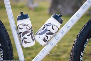 Two patterned water bottles in King Cage stainless cages on the Donard down tube and seat tube.