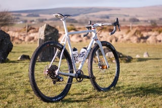 Donard x Victory Chimp Gairbhéal bike parked on grass among standing stones, with two patterned bottles on the frame.