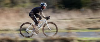 Panning shot of a rider at speed on a white Surly Midnight Special against a blurred background.
