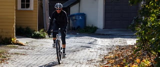 Helmeted rider on a Surly Midnight Special coming down a brick-paved back alley in autumn.