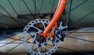 Gorilla Monsoon front fork leg with disc brake caliper, rotor and thru-axle on an orange steel fork.