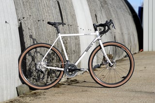 Surly Midnight Special in white with tan-wall tyres against a curved concrete wall.