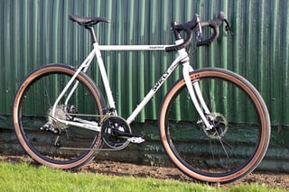 Surly Midnight Special leaning on a green corrugated metal wall, standing on grass.