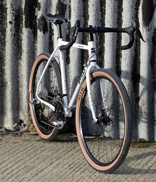 Front three-quarter view of the Surly Midnight Special with SRAM levers and WTB Horizon tyres by a weathered concrete wall.