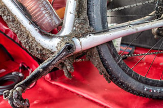 Mud-caked Middleburn crank arm, XTR pedal and down tube of the Salsa Cutthroat, the bike lying on a red mat.