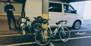 Surly Midnight Special and a second bike propped by a van in a car park before the ride, with a person nearby.