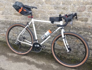 Surly Midnight Special loaded with saddlebag, top-tube bag and bottle for the 200km audax, against a stone wall.