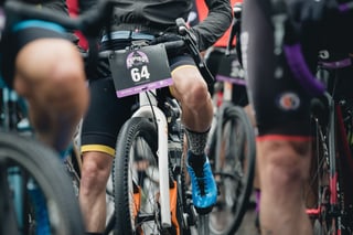 Riders at the start of Grinduro Scotland, with number 64 on the bars of a white gravel bike.