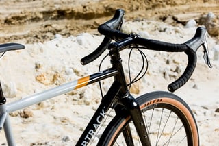 Bombtrack Audax drop bars with black tape, brake levers and a gloss black head tube and fork.