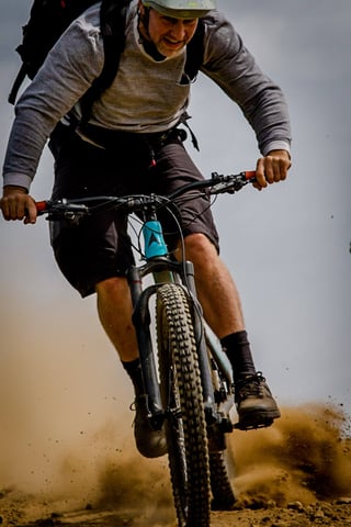 Mountain biker in a grey top kicks up a spray of dust on a dirt track at Yorkshire True Grit.