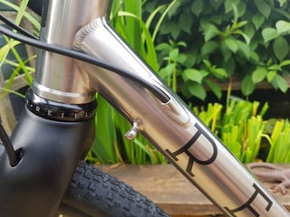 Reilly Gradient head tube and brushed titanium down tube, with the rear brake hose entering the tube below the headset.