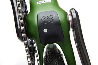 Black Kona-logo cover over the bottom bracket of the green Libre DL, with the chain and crank arm either side.