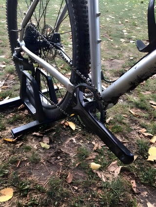 Crank, chain and rear cassette on the silver Bombtrack Hook ADV, held in a workstand on leaf-strewn grass.