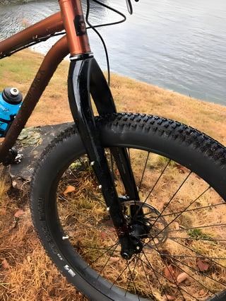 Rigid carbon fork and plus-size Trail Boss tyre on the Bombtrack Beyond+ 2, with the copper frame behind.