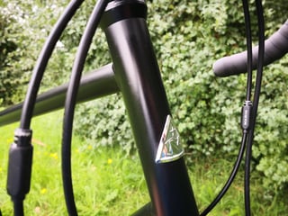 Head tube badge and cable run on the Marin Four Corners steel frame, with the bar tape behind.