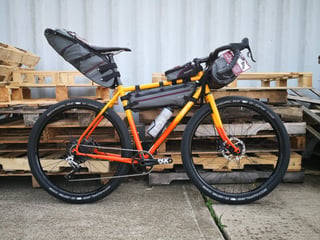 Side view of the All-City Gorilla Monsoon with frame, seat and handlebar bags, and a bottle in the cage.