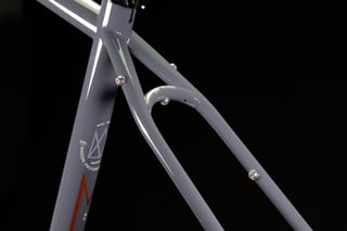 Studio detail of the grey Mason ISO seat tube, seatstay bridge and mounting eyelets against a black backdrop.