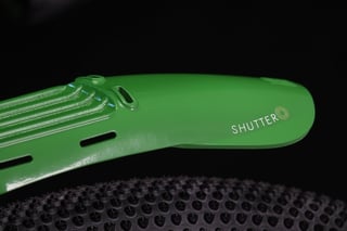 Close-up of the green Shutter mudguard for the Mason ISO, with its strap slots, above a knobbly tyre.