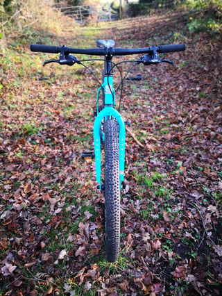Head-on view of the Surly Bridge Club on a leafy track, showing its flat bar, Avid levers and knobbly front tyre.
