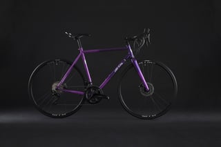 Purple All-City Zig Zag steel disc road bike in side view against a dark studio backdrop.