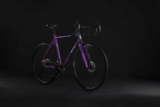 Purple All-City Zig Zag disc road bike with drop bars, three-quarter front view on a dark studio background.