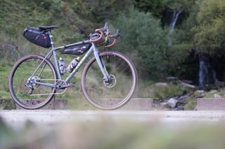 Trek Crockett 7 gravel bike fitted with bikepacking bags, parked on a track beside a rocky Welsh stream.