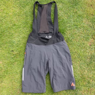 Front of the Aussie Grit Apparel Ignite 2-in-1 bib shorts on grass, with reflective leg stripes and a zipped pocket.