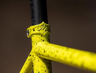 Cast All-City seat tube collar on the yellow splatter-painted Macho King frame, close up.