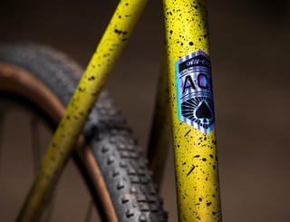 A.C.E. steel tubing decal on the seat tube of the yellow All-City Macho King, with a knobbly tyre behind.