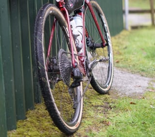Low rear view of the Cervelo Aspero on WTB Venture 40 tyres, showing its SRAM drivetrain beside a green shed.