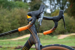 Salsa Warroad drop bars with SRAM Force shifters, orange Arundel Art Gecko bar tape and a bronze stem spacer.