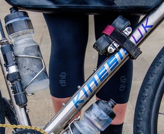 Kinesis logo on the titanium downtube of the Tripster V3, with two Lezyne bottles and a spare tube strapped on.