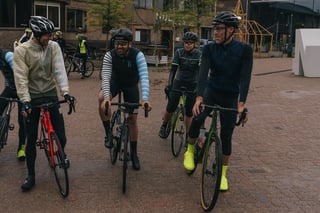 Riders laugh and chat on their bikes before the Scope Backyard Breakaway rolls out of Eindhoven.