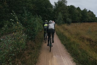 Riders follow a sandy gravel track between pine trees and heathland on the Backyard Breakaway course.