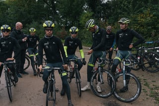 Wallonie-Bruxelles pro continental team riders and staff gather on a muddy track at the Backyard Breakaway.