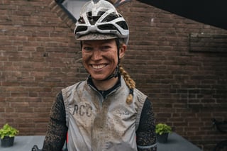 Smiling rider with a mud-splashed face, helmet and Rapha gilet after the Scope Backyard Breakaway.